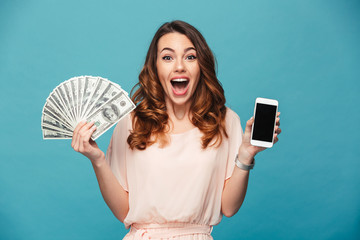 Excited young lady showing display of mobile phone holding money.
