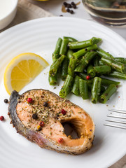 Healthy food. Baked red fish, pink salmon, salmon and green beans with a slice of lemon on a plate.