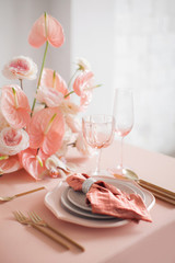 Festive table decor. In pastel pink colors with golden cutlery. With different natural colors roses, peonies, anthurium. Luxury wedding, party, birthday. View from above