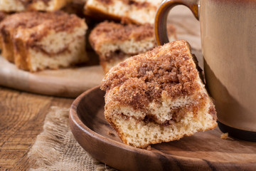 Closeup of a piece of cinnamon swirl crumb cake and coffee cup on a wooden plate