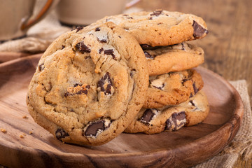 Closeup of chocolate chip cookies on a wooden plate - obrazy, fototapety, plakaty