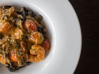 Black Spaghetti in tomato sauce with shrimp, tomato sprinkle with spices and cheese on white plate.Fresh and clean dishes look delicious and yummy