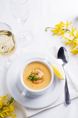 Creamy soup with seafood and lemon on a white background.