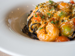 Black Spaghetti in tomato sauce with shrimp, tomato sprinkle with spices and cheese on white plate.Fresh and clean dishes look delicious and yummy