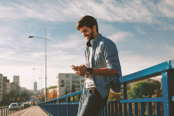 Young happy man using a smartphone  in the city
