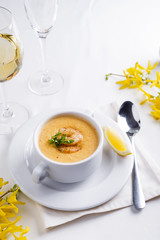 Creamy tomato soup with seafood and lemon on a white background.