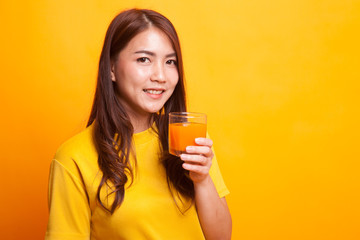 Young Asian woman drink orange juice in yellow dress