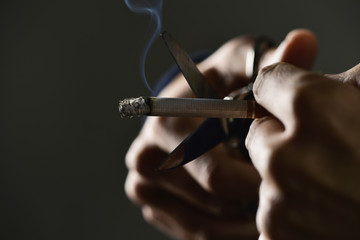 man cutting a lit cigarette with scissors