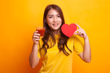 Young Asian woman with tomato juice and red heart in yellow dress