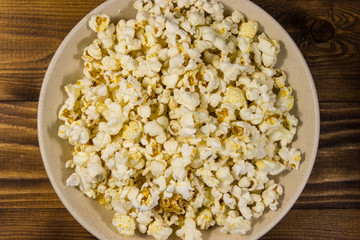 Bowl with popcorn on wooden table