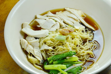 Chinese egg noodles with chicken meat in brown soup on bowl