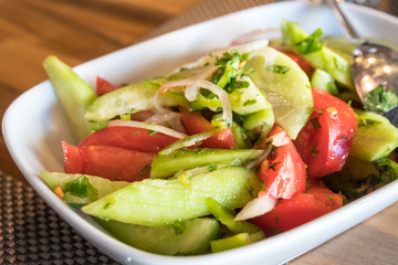 Tomato and cucumber salad with onion, pepper and parsly