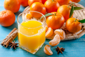 Orange juice, tangerines and cinnamon on wooden background