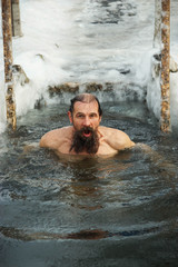 A middle-aged man is immersed in an ice hole.