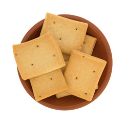 Top view of several hard bread crackers in a small red clay bowl isolated on a white background.