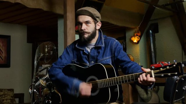 Handsome bearded musician playing guitar in the pub.