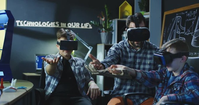 Group of kids with teacher testing VR manipulator in virtual goggles having class.