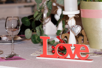 A modern wedding decoration for the ceremony with the inscription Love and glasses lies on a light tablecloth on the table. Side view, selective focus