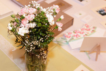 Delicate bridal bouquet of fresh flowers on a light tablecloth with greeting cards. Side view, selective focus