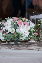 A wedding bouquet of fresh white and pink flowers stands on a white table. Side view, selective focus
