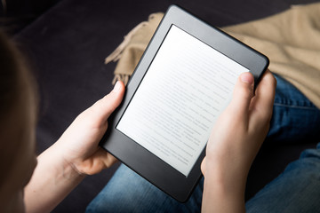 Girl is reading ebook on digital tablet device - obrazy, fototapety, plakaty