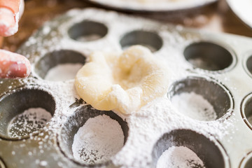Hands, piece of mochi sticky glutinous rice cake dusted with starch flour to make dessert in muffin pan tin