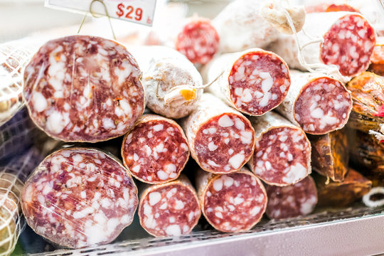 Closeup of sopressata and genoa salami rolls on display in a market shop butcher, price per pound