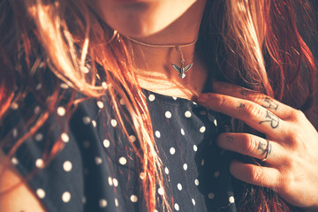 Young beautiful girl looks like the tattoo artist does the tattoo, reading the news in the smartphone