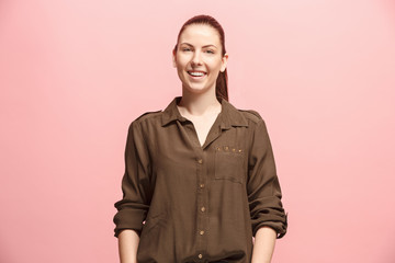 The happy business woman standing and smiling against pink background.