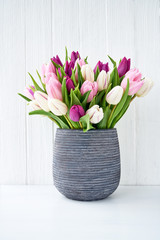 Pink and white tulips bouquet in gray vase. Holiday concept