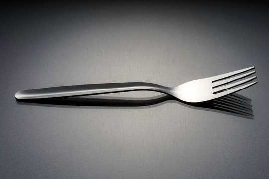 Image of a silver fork over black background. 