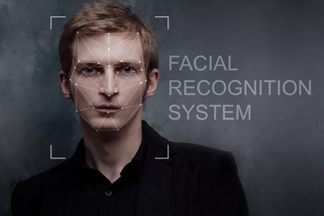 Facial recognition system, concept. Young man on grey background, face recognition