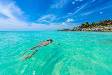 Attractive young woman relaxing in turquoise waters of Caribbean Sea in front of paradise beach in Tulum, close to Cancun, Riviera Maya, Mexico