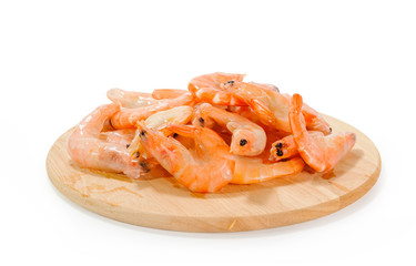 Pile of shrimps in ice shell on round wooden plank on white background