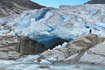 Ice front and glacier gate of Nigardsbreen (Norway) with careless hikers too close to the dangerous...