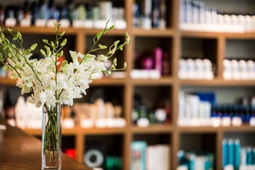 Foto op Plexiglas Schoonheidssalon цветы в вазе на фоне стеллажа с косметикой в салоне красоты 