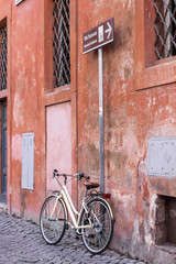 bicicletta legata ad un palo in un vicolo di roma centro