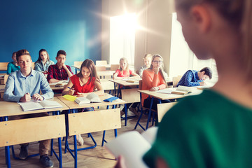 group of students and girl with notebook at school