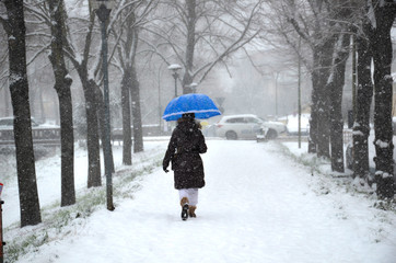 Ragazza cammina nella neve con ombrello blu