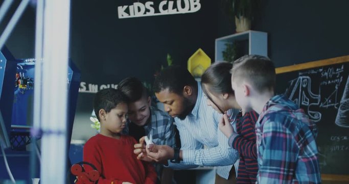 African-american man conducting class with group of kids having club and discussing robotics and technologies. Movement 4K shot on Red cinema camera.