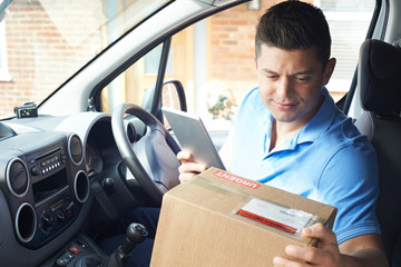 Courier In Van With Digital Tablet Delivering Package To House