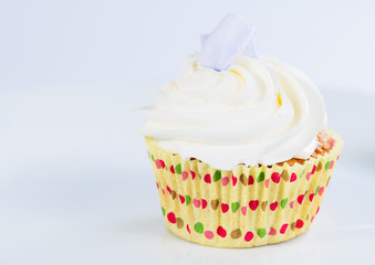 Appetizing sweet dessert. White glaze cupcake with cream on light background