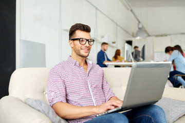 smiling man with laptop working at office