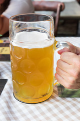  A huge mug of cold beer held by a thirsty man