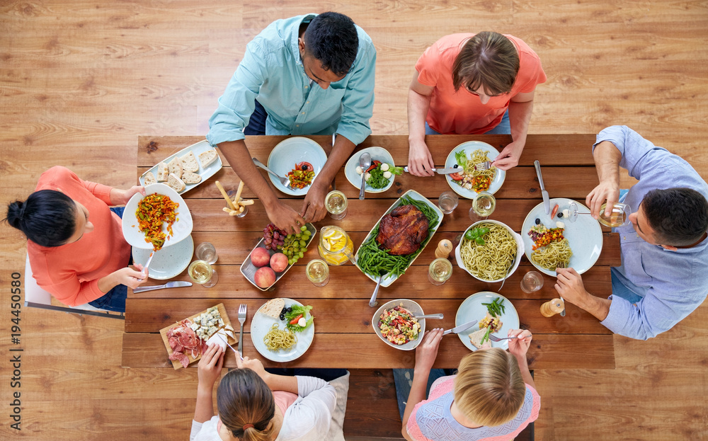 Wall mural group of people eating at table with food