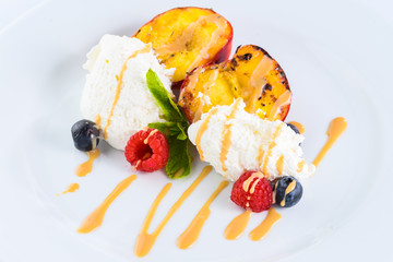 Sweet appetizing dessert with ice-cream, apricot, berries and mint in a white plate, for menu design
