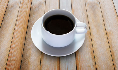 black coffee in white cup on wooden board.