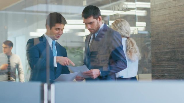 Two Businessmen Shaking Hands in the Corporate Building Hallway, They Compare Documents
