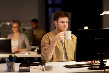 man with laptop and coffee working at night office