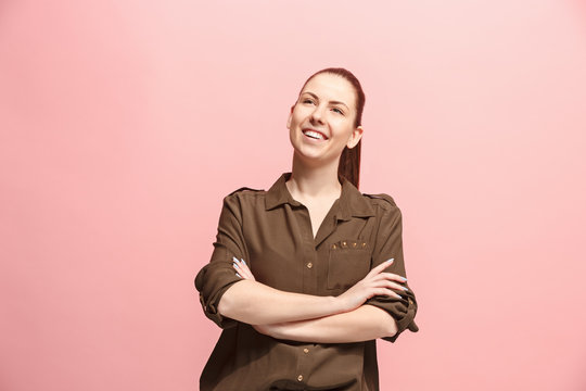 The happy business woman standing and smiling against pink background.